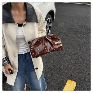 Detail of dark brown pleated cloud bag with shiny patent leather and gold stud accents