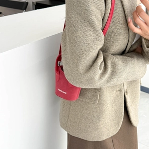 Mini borsa a secchiello rossa in pelle scamosciata con scritta su giacca marrone