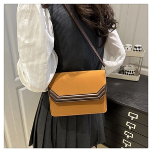 Detail view of mustard yellow suede patchwork crossbody bag worn on a woman waist