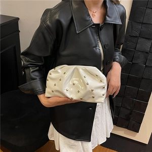White ruched cloud clutch bag with gold studs and chain strap held by model