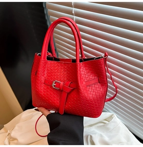Close-up of red woven handbag with silver buckle detail and matching shoulder strap