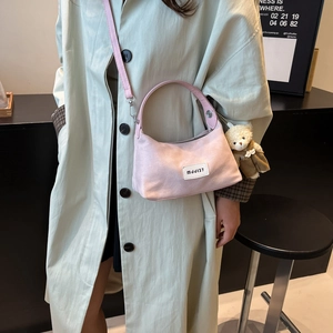 Pink suede hobo dumpling bag for women featuring a teddy bear charm and logo patch