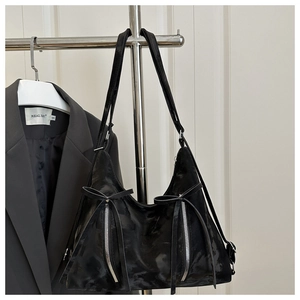 Detail of black faux leather tote with silver dual zippers and long bow tassel decoration