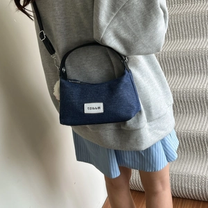 Retro dark blue denim crescent bag with black leather handle and white logo patch
