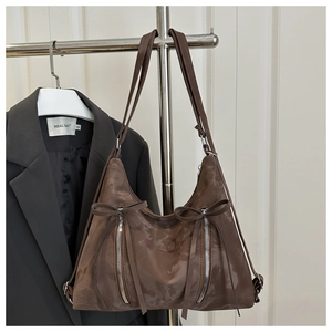 Close-up of brown suede tote bag featuring front bows and metal zipper details