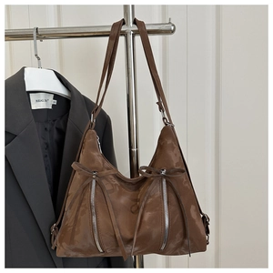 Detailed macro view of dark brown tote bag with metal zippers and leather bow ribbons