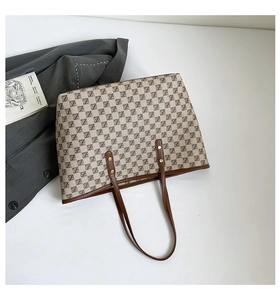 Dettaglio della borsa tote vintage con monogramma, manici in pelle e rivetti