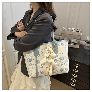 Detail of canvas tote bag with blue graffiti prints and a cute plush bunny charm