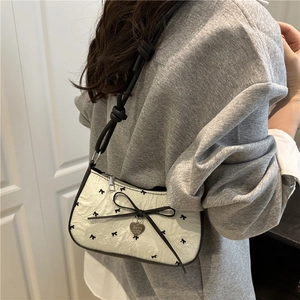White crescent underarm bag with black bow print and heart charm for women