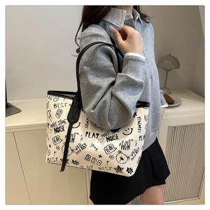 Detail of white canvas tote bag with black graffiti print and sturdy black shoulder straps