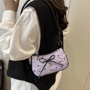 Purple crescent underarm bag with black bows and a metallic heart pendant
