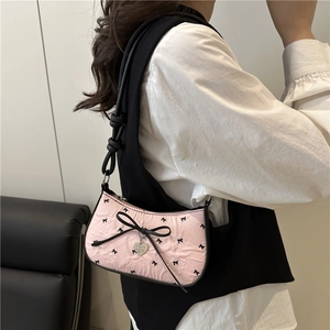 Pink crescent underarm bag with black bows and heart pendant shown on model