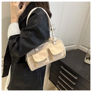 Detailed side view of a cream canvas handbag worn by a model in a minimalist home setting