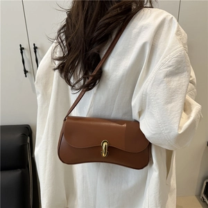 Sac sous le bras vintage marron en cuir avec boucle dorée présenté sur un mannequin