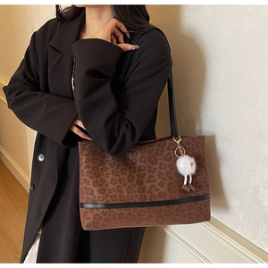 Détail du grand sac cabas léopard avec pendentif en peluche porté par le modèle