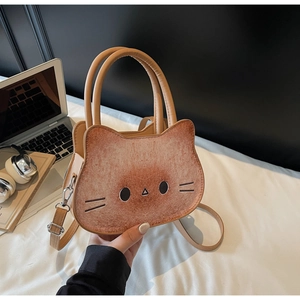 Detail of cute cat-shaped toast crossbody bag in brown PU leather on a white bed