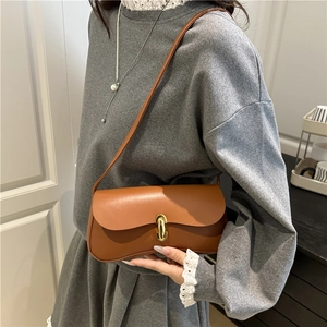 Sac à bandoulière en cuir marron de style français avec boucle dorée porté par un mannequin