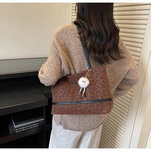 Détail du sac cabas léopard avec bandoulière en cuir noir et charm en peluche blanc