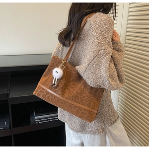 Détail du sac cabas léopard avec anses en cuir marron et pendentif peluche doux