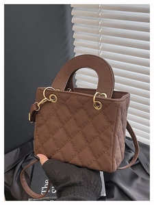 Detail of dark brown quilted crossbody bag with round handle and gold-tone hardware