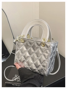 Detail of silver quilted handbag with metallic finish and gold hardware handle rings