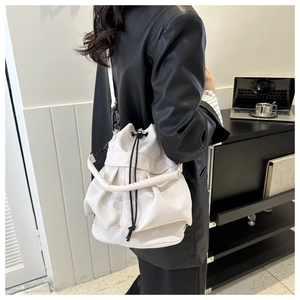 Detailweergave van de crèmekleurige bucket bag met trekkoord en geplooide nylon textuur