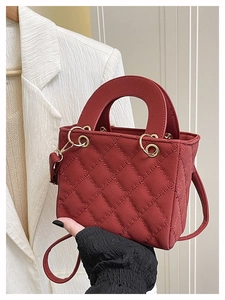 Detail of red quilted square handbag with gold metal rings and sturdy top handle