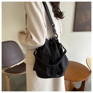Detail van een zwarte bucket bag met trekkoord en verstelbare stoffen schouderband voor dames
