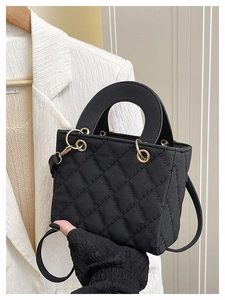Close-up of black quilted mini handbag with round handle and metallic D-ring details