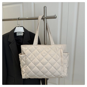 Detail of cream quilted tote bag showing nylon texture and side pocket for daily commuting