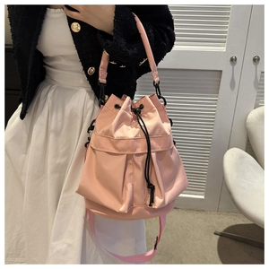 Gros plan du sac seau à cordon rose clair avec poches latérales et détails métalliques noirs