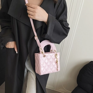 Pink quilted leather handbag with crossbody strap and metallic charm details