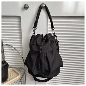Gros plan du sac seau en nylon noir avec cordon de serrage et large bandoulière en tissu
