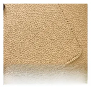 Détail du similicuir beige à grain de litchi avec des coutures précises sur le bord