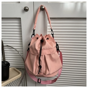 Détail du sac seau plissé rose avec cordon de serrage, boucles noires et bandoulière