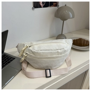 Gros plan d'un sac bandoulière en velours côtelé crème avec double fermeture éclair et cordon