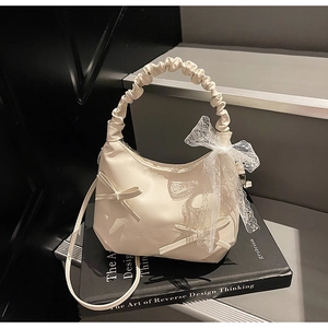 Close-up of cream-white ruffled handbag with lace bows and smooth PU leather texture