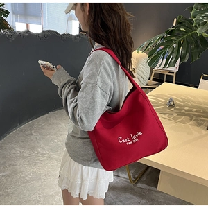 Detail of red canvas tote bag with C'est la vie white lettering and brand logo print