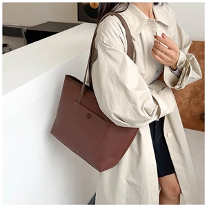 Détail d'un sac cabas en cuir marron avec texture litchi et poche avant pratique