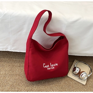 Detail of red canvas tote bag with white lettering on premium textured fabric