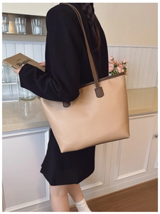 Detalle del bolso tote caqui cálido con estampado dorado y asas en color marrón oscuro