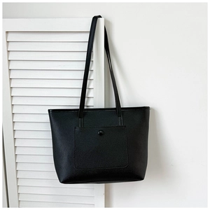Détail d'un sac cabas noir à grain litchi avec poche avant et boucle ronde élégante