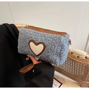 Détail du sac cylindre en sherpa bleu clair avec patch cœur et dragonne en similicuir brun