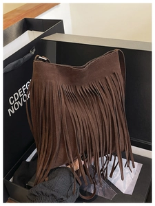 Detail of dark brown faux suede shoulder bag featuring long bohemian fringe decoration