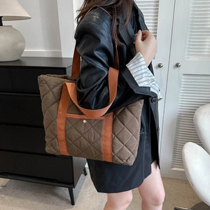 Quilted tote bag in dark brown with orange straps featuring a rhombus pattern