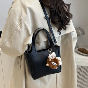 Retro black pebble leather bucket bag with plush charm shown on a female model