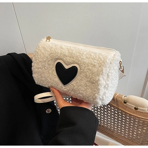 Détail du sac cylindrique en peluche blanche avec patch cœur noir et fermeture dorée