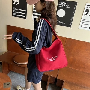 Large red canvas hobo tote bag with stylish white lettering print in a trendy urban setting