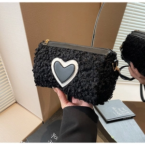 Détail du sac cylindre en peau d'agneau noire avec écusson cœur et zip doré élégant
