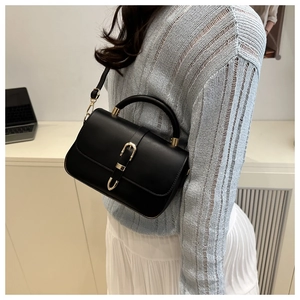Gros plan d'un sac selle en cuir PU noir avec boucle dorée sur un mannequin au style épuré